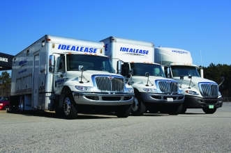 Three white International® trucks sitting in the lot of a truck leasing office on a sunny day.