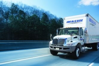 White International® box truck driving down the highway with trees in the background on a sunny day.