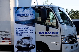 White box truck with Idealease on the door sitting by an Idealease sign.